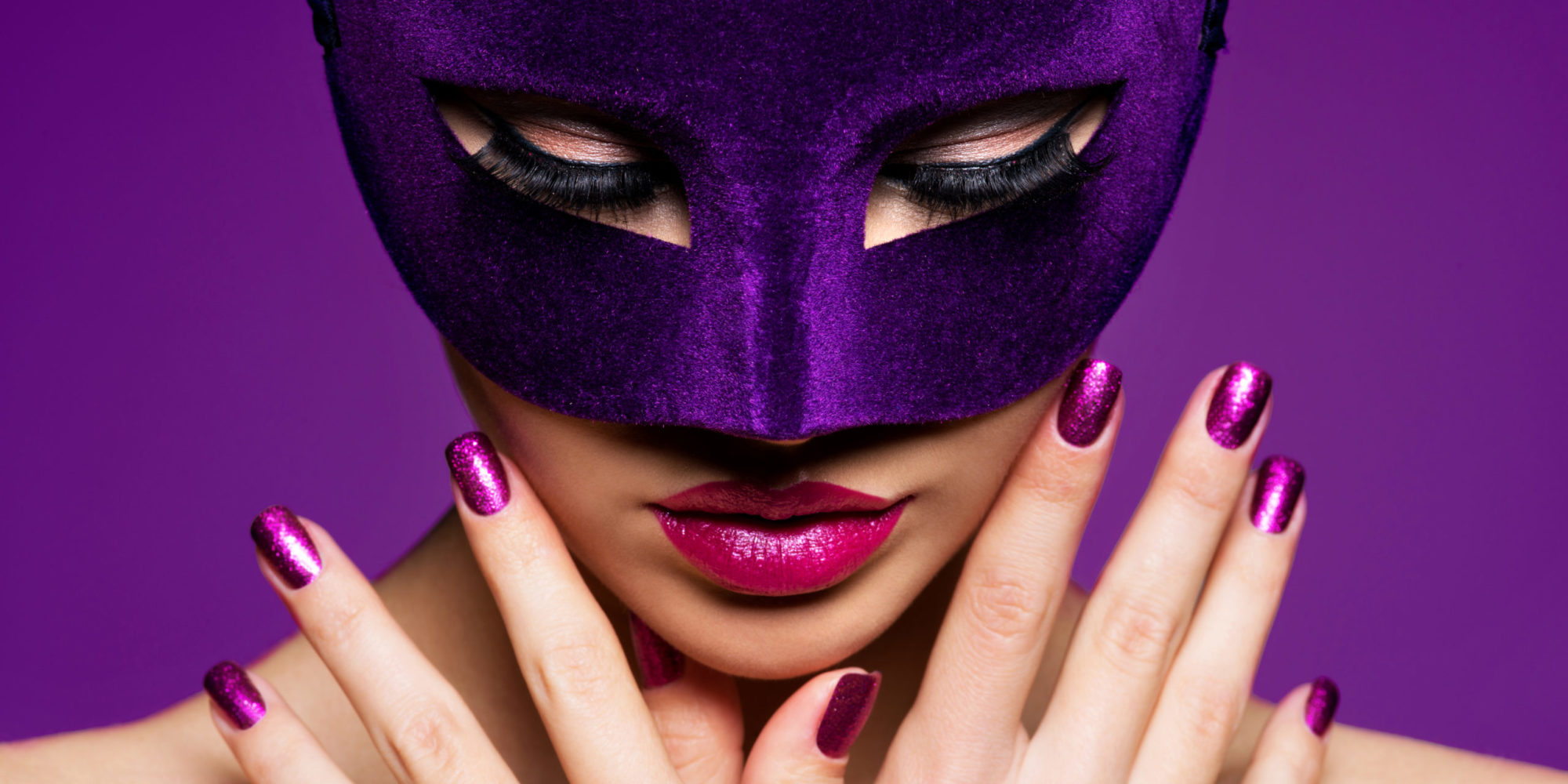 Portrait of a beautiful  woman with purple nails and violet theatre mask on face.